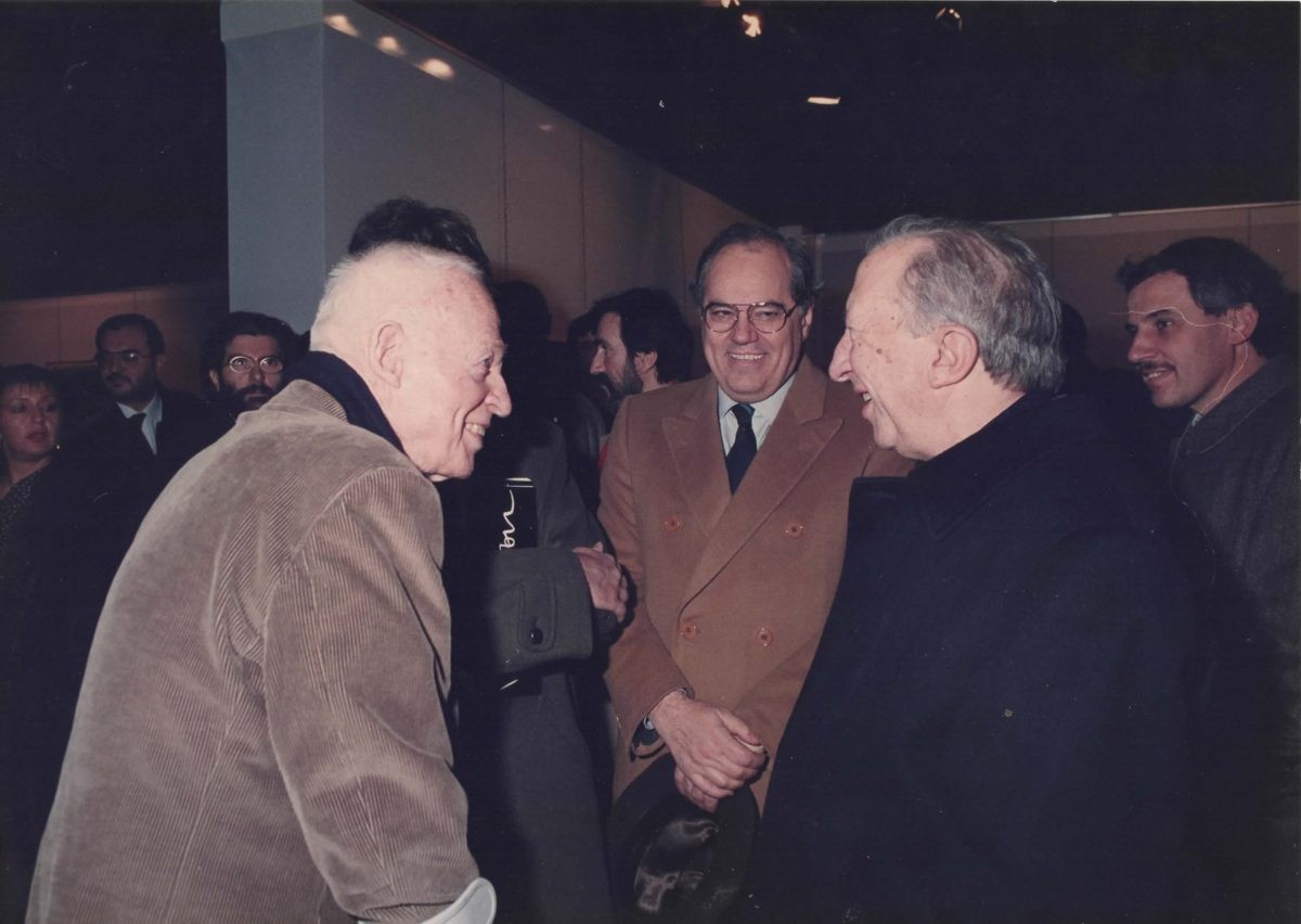 Peppino Zola conversa sorridendo con altre personalità durante un incontro pubblico